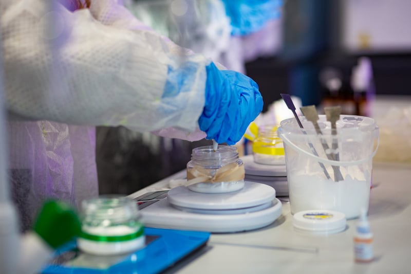 Лаборант у рукавичках готує зразок у баночці під час експерименту