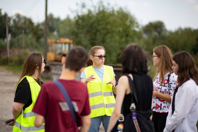 Жінка у жовтому жилеті проводить екоекскурсію для молоді
