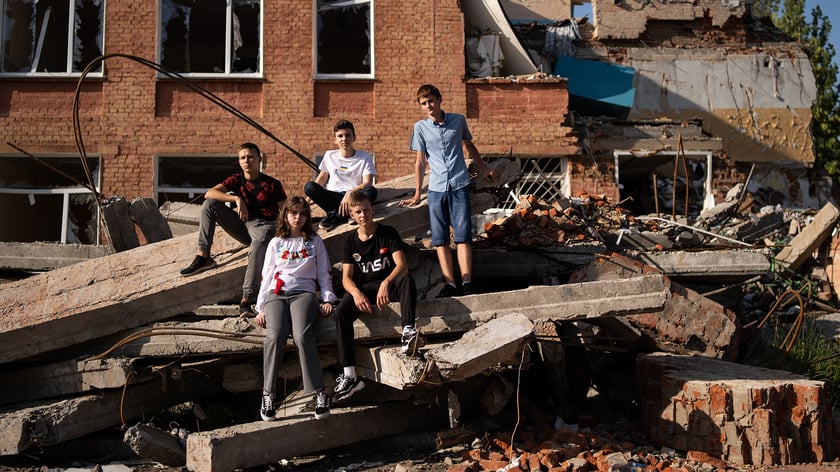 Українські діти на фоні зруйнованої будівлі